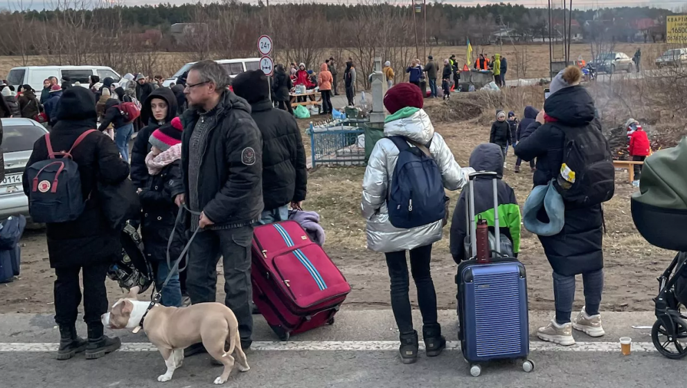 Refugees stand in line as they wait for a bus to the border checkpoint at Rava Ruska, Ukraine