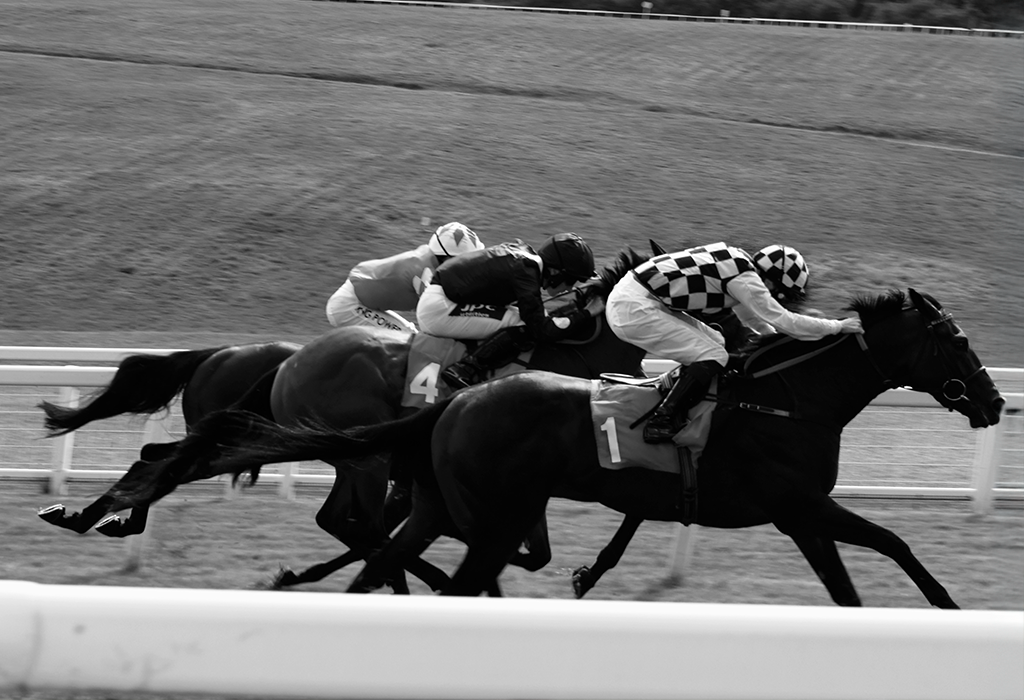 Black and white picture of horses and riders on track
