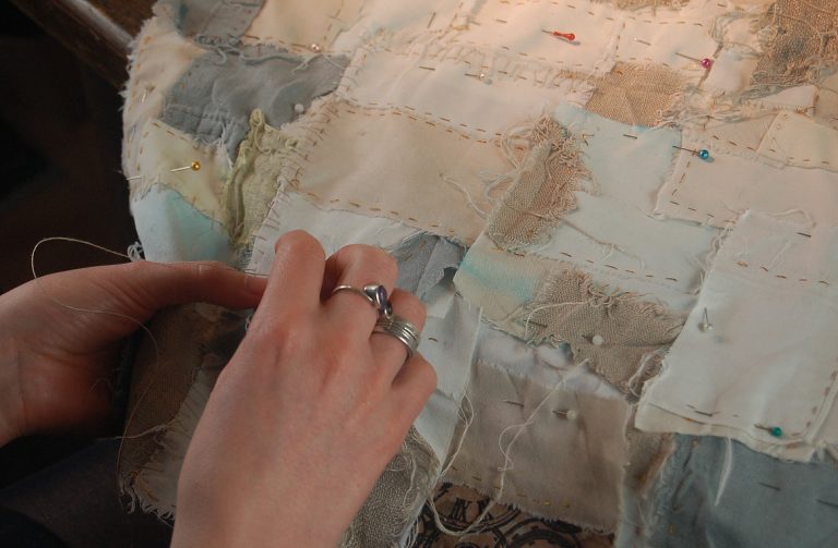 picture of the hands of a person stitching pieces of fabric together